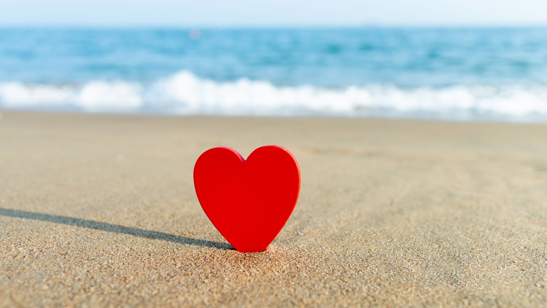 Un cœur posé sur du sable à la plage