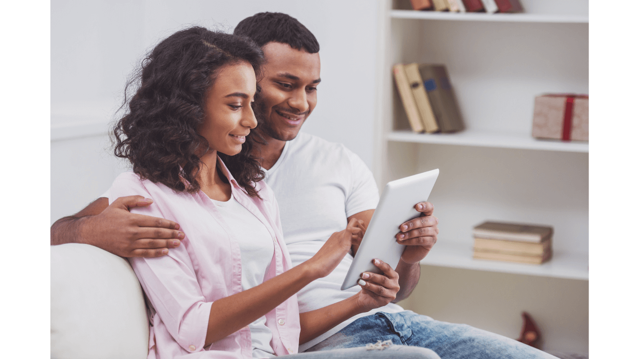 Une femme noire et un homme noir regardant une tablette tactile