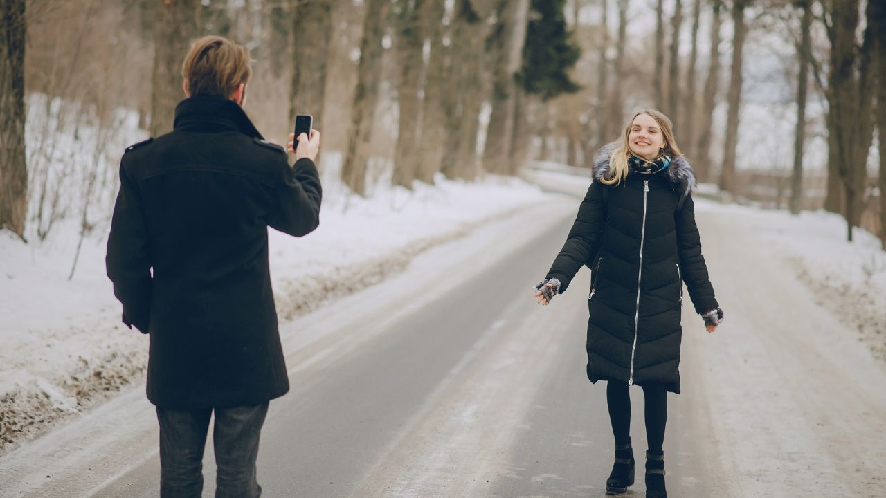 Dans la neige, une femme se fait photographier pour une photo de rencontre en ligne