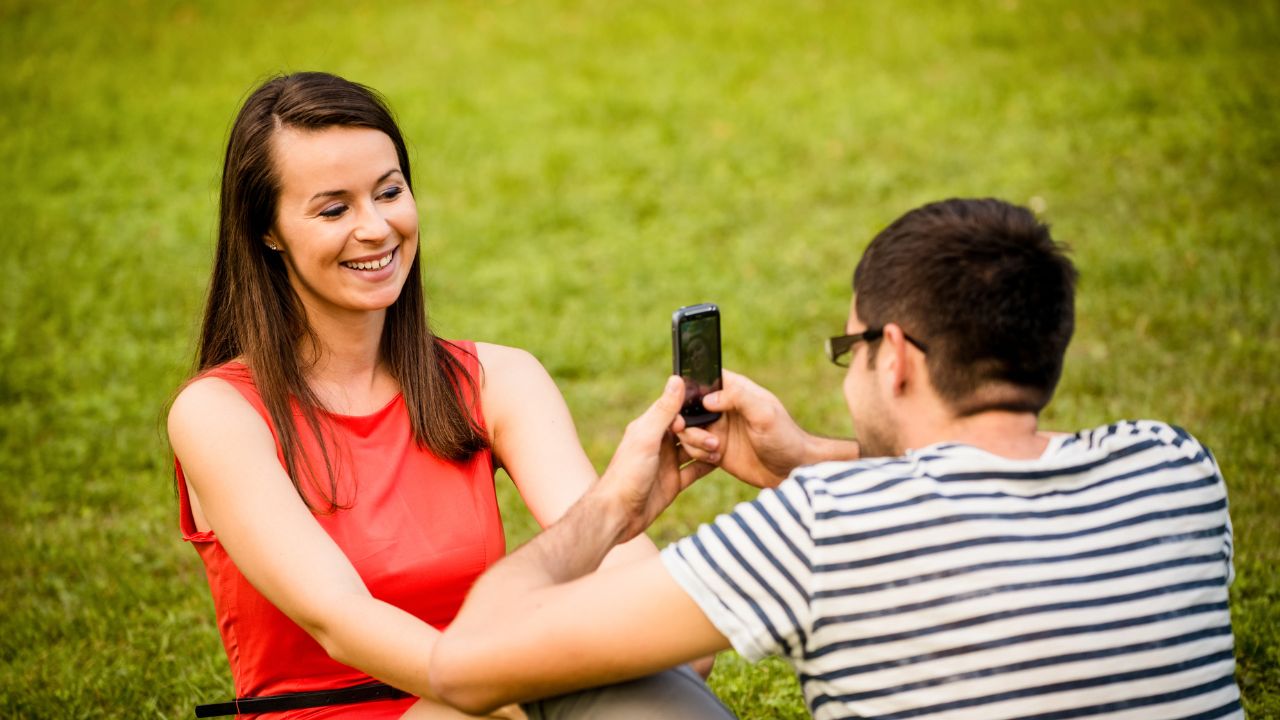 Un homme qui prend en photos une femme dans un parc