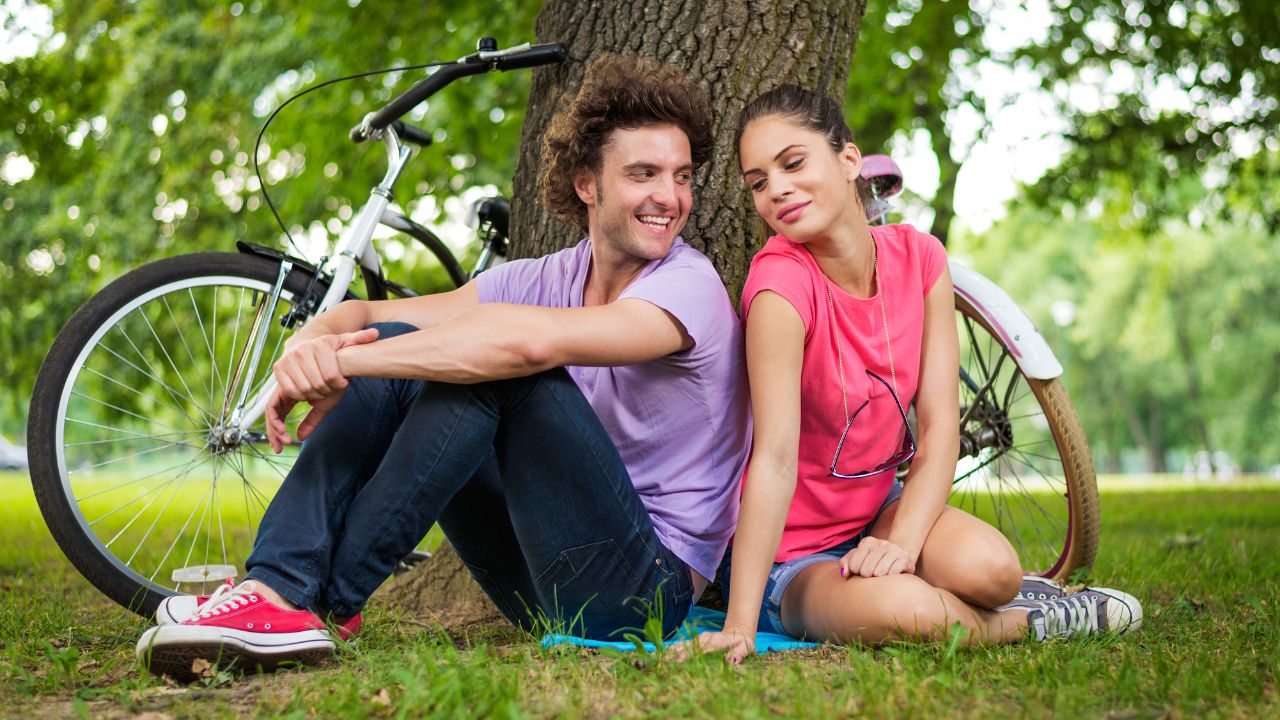 Un couple amoureux dans un parc avec un vélo à coté