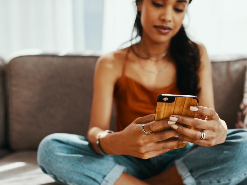 Une femme métisse qui est en train d'écrire un message sur un site de rencontre